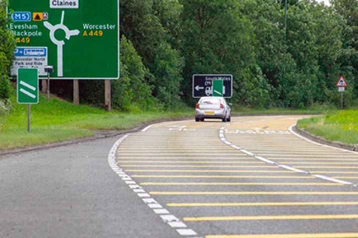 Yellow lines painted across a road on the approach to a roundabout